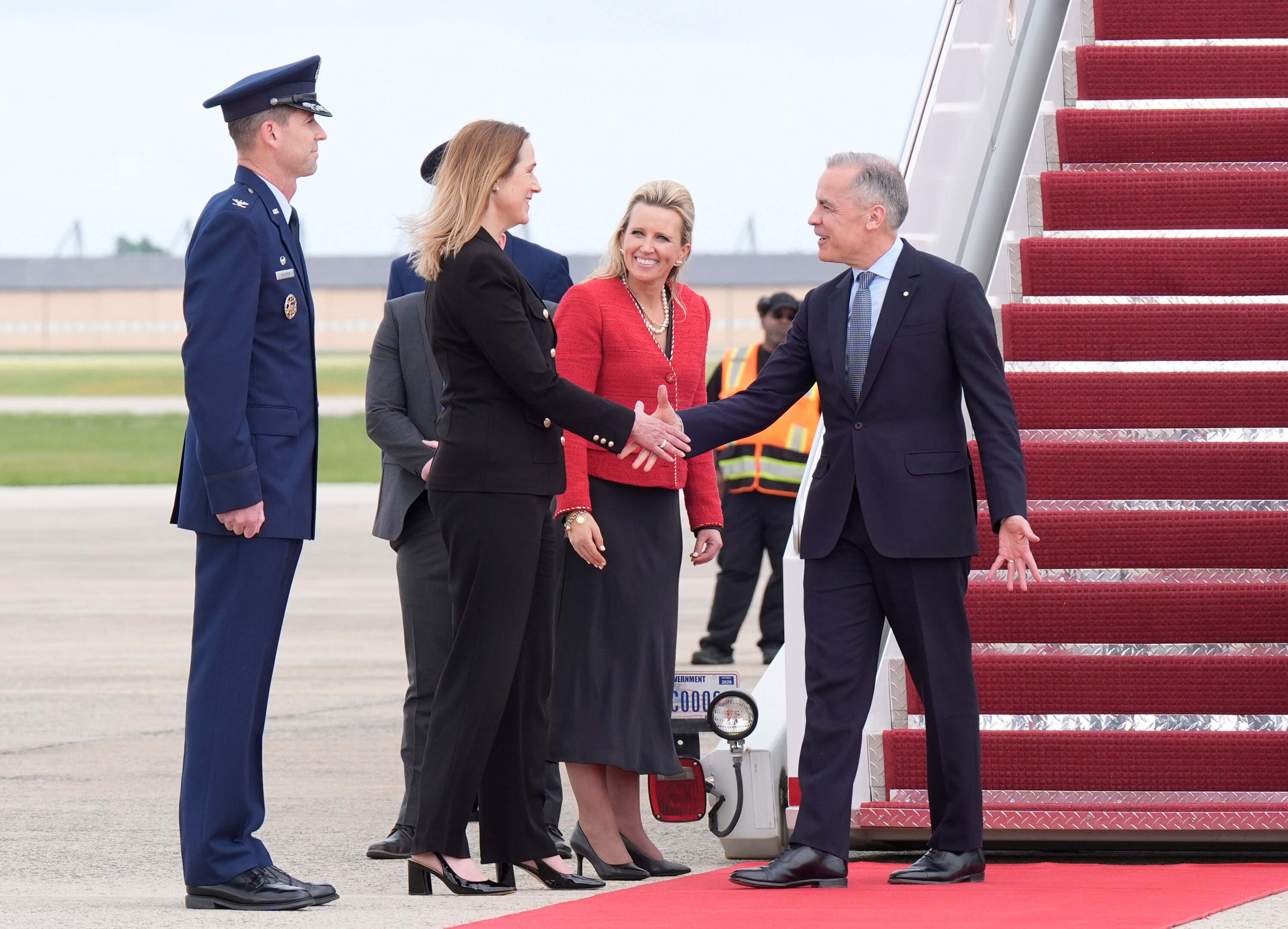A man wearing a suit shakes hands with a woman