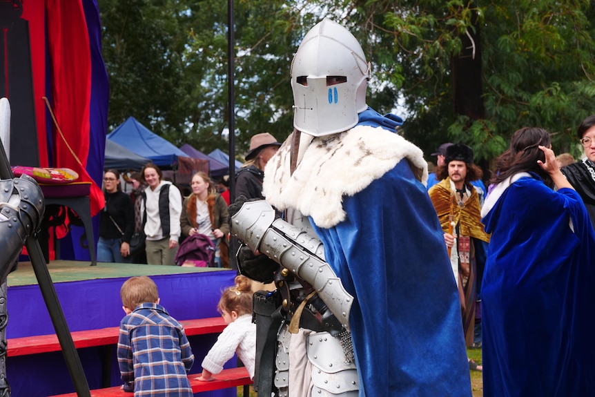 A man dressed in silver armour stands in a crowd