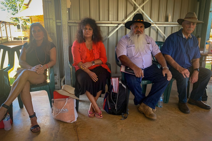 Senators including Lydia Thorpe and Mick Dodson sit on plastic chairs in a large corrugated shelter..