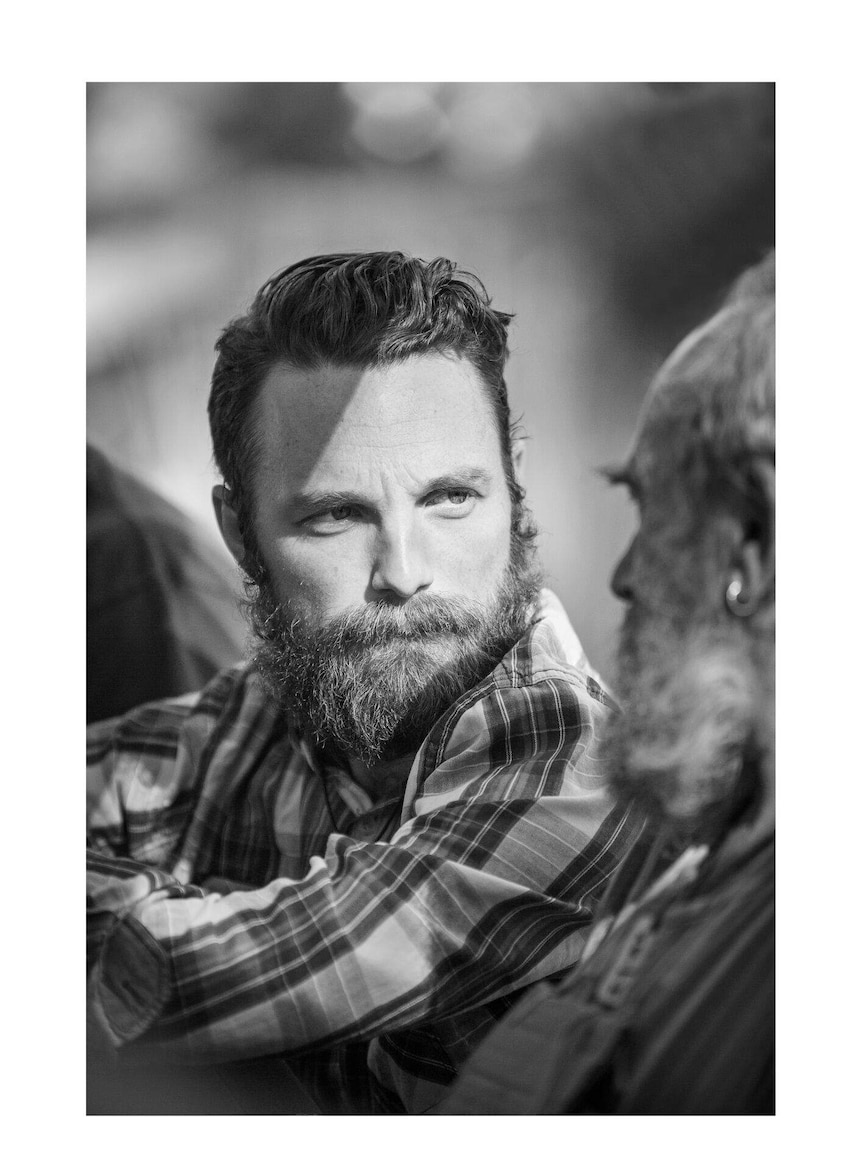 A young man with beard looks at older man - Men With Heart exhibition.