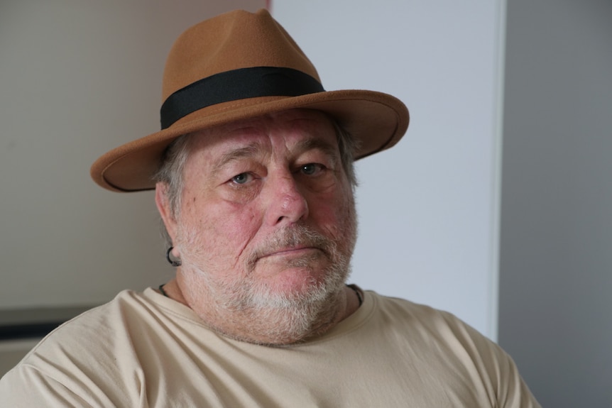 Paul Klotz, wearing a fedora, stares seriously into the camera