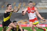 Jordan Dawson kicks a yellow ball past Daniel Rioli, who is approaching from Dawson's right with his arms raised