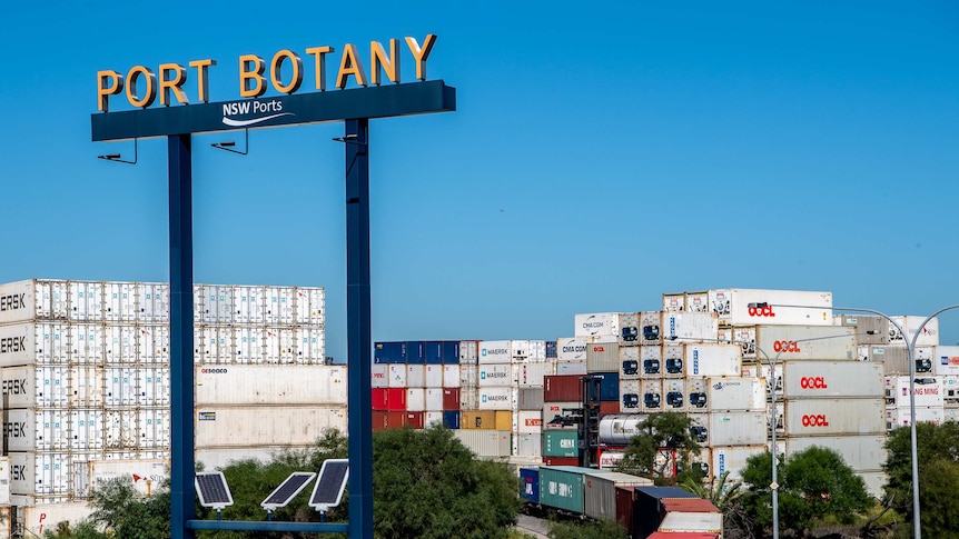 Shipping containers stacked high near the Port Botany sign.