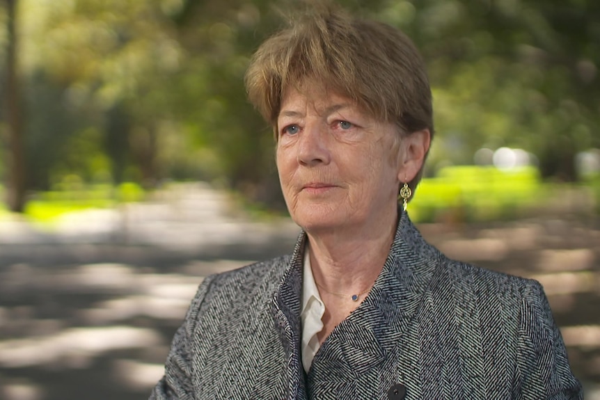 Catherine Cusack wearing a gray jacket and sitting in a park.