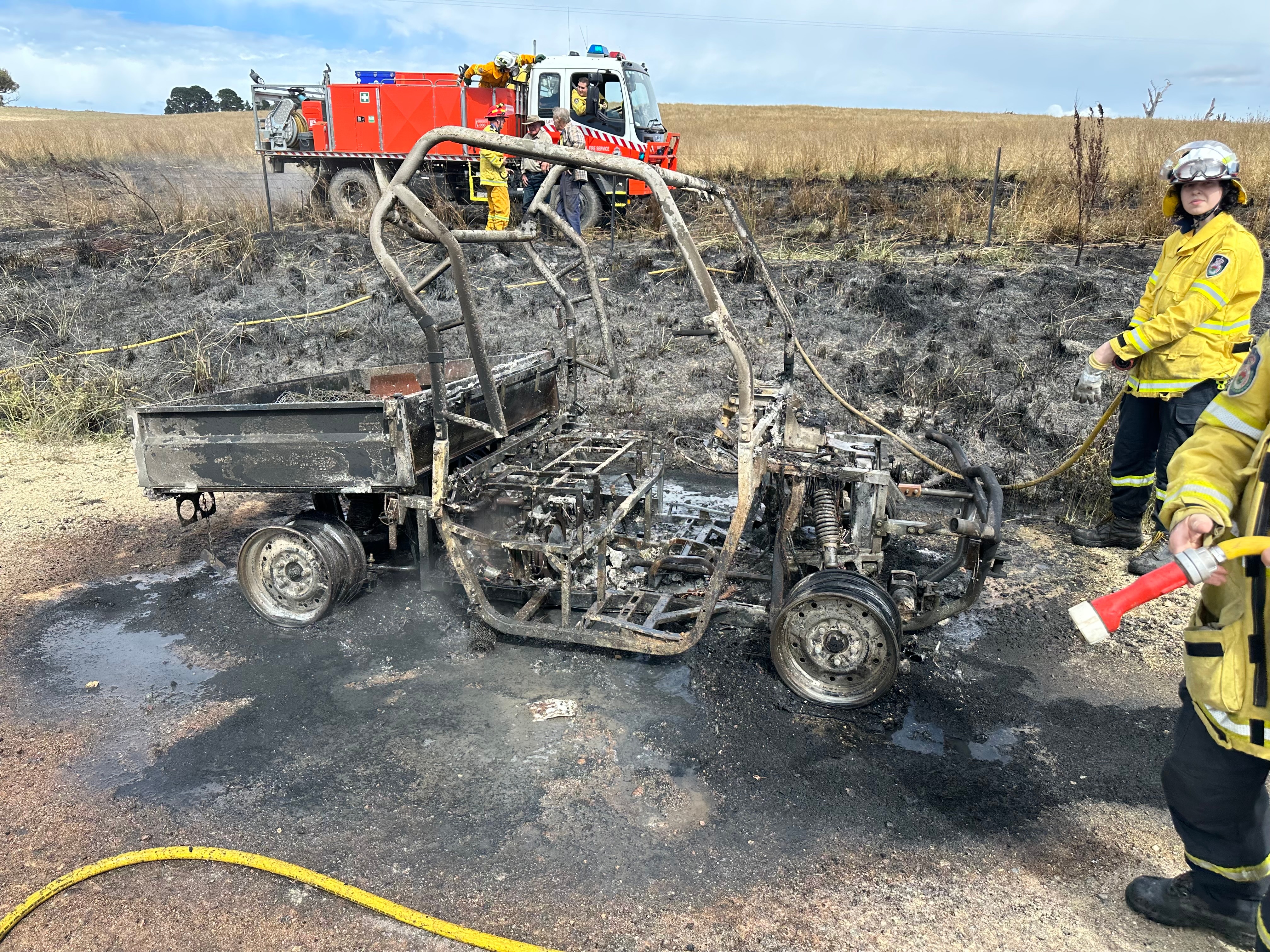 rfs volunteers put out side by side fire in paddock