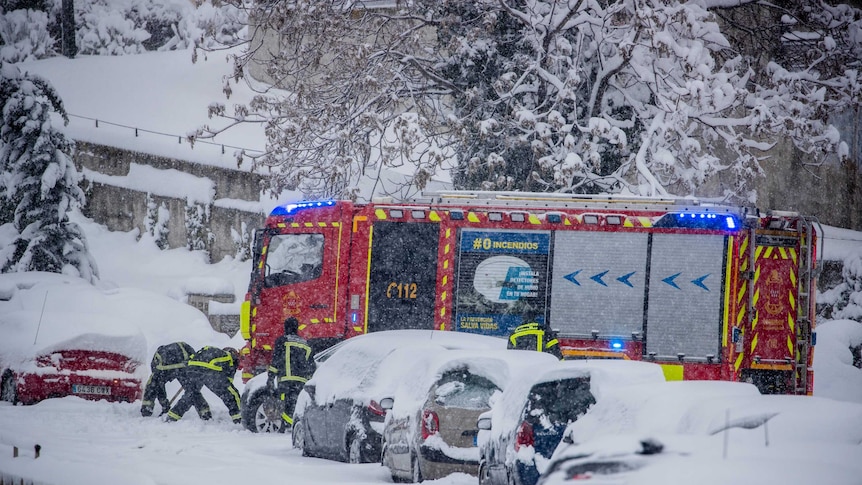Emergency workers rescue people in cars trapped under heavy snow.