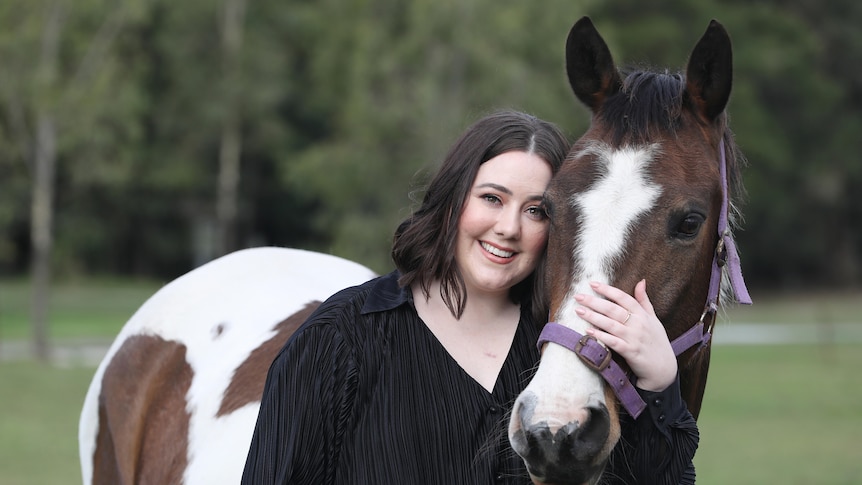 A woman with her arm around a horse.