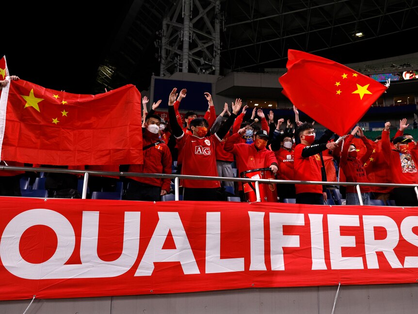 A group of Chinese football fans waving flags. 