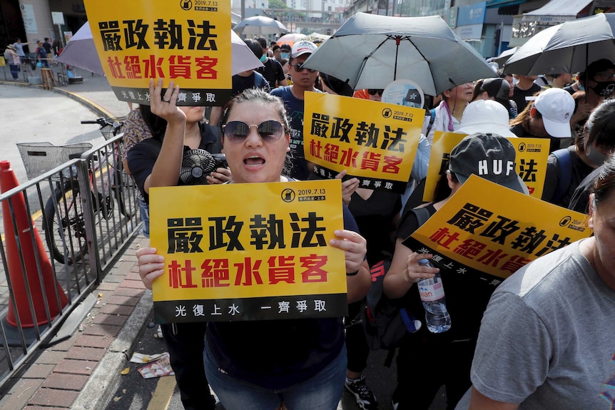 Protesters hold up words that read: "Strict enforcing of law against smugglers of grey goods".