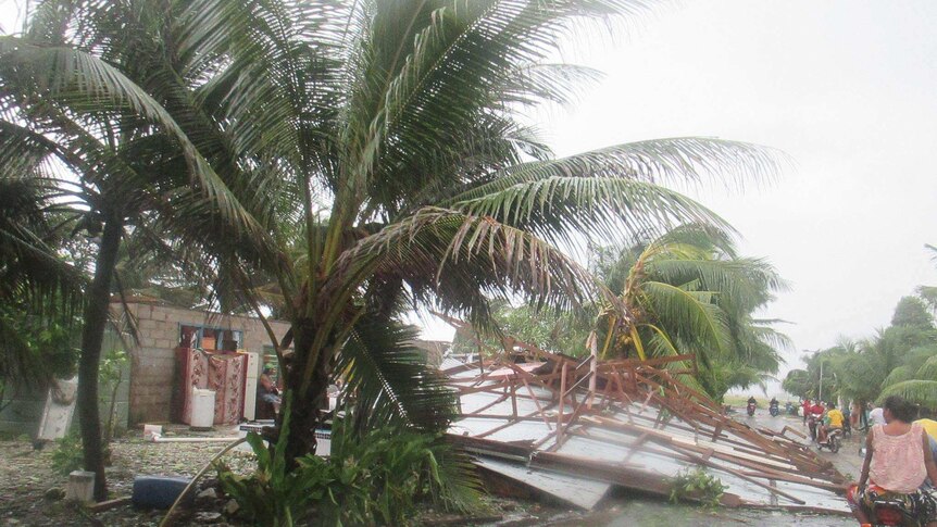 A house blown over in Tuvalu obstructs a main road