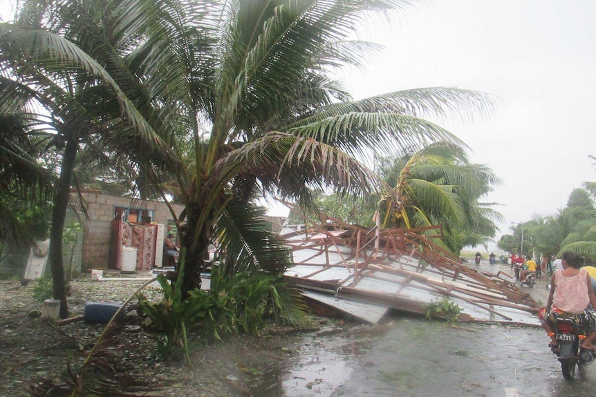 A house blown over in Tuvalu obstructs a main road