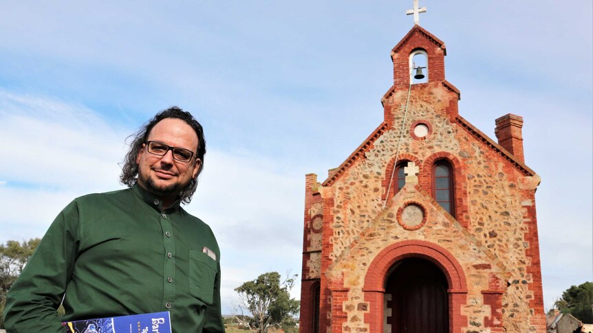 man standing in front of old stone church