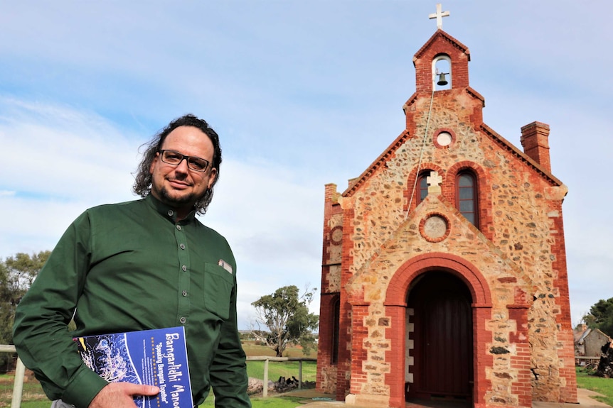 man standing in front of old stone church