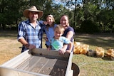 A family of four stand by a giant sieve they use to hunt for gemstones.