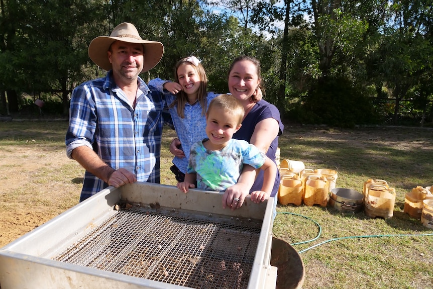 A family of four stand by a giant sieve they use to hunt for gemstones