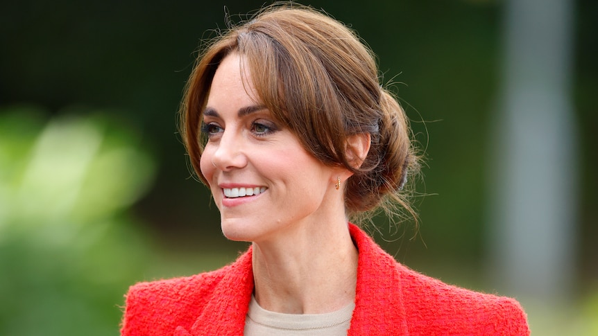 A close up of the princess smiling. She wears a bright red blazer and her brown hair is in a low bun