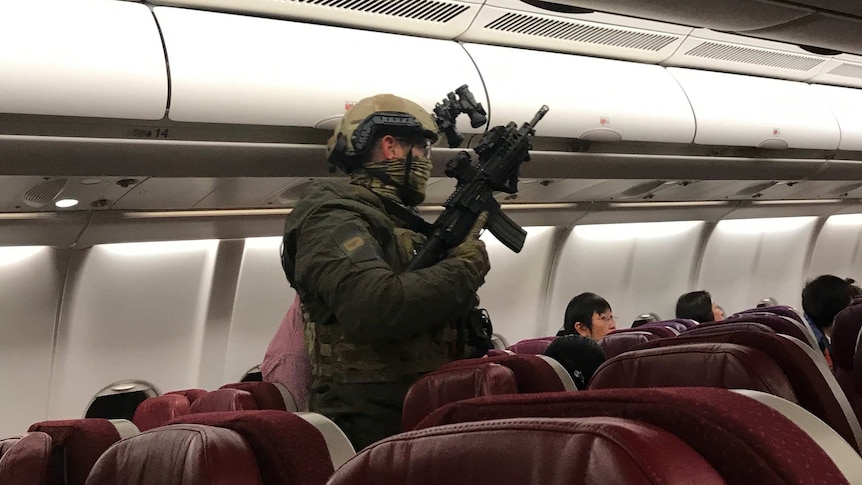 A heavily armed police officer is seen onboard a Malaysia Airlines plane.