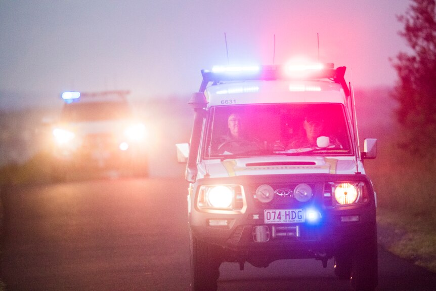 Ambulances with lights on travelling down a dirt road