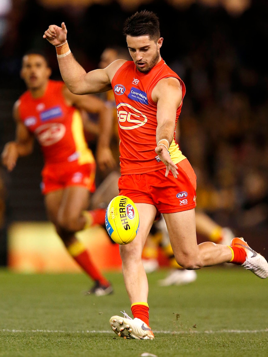 An AFL player about to kick a football