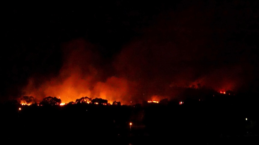 Flames from a grass fire at Oxley in Canberra glow in the night sky.