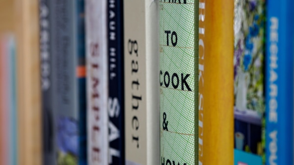 A row of cook books on a shelf.