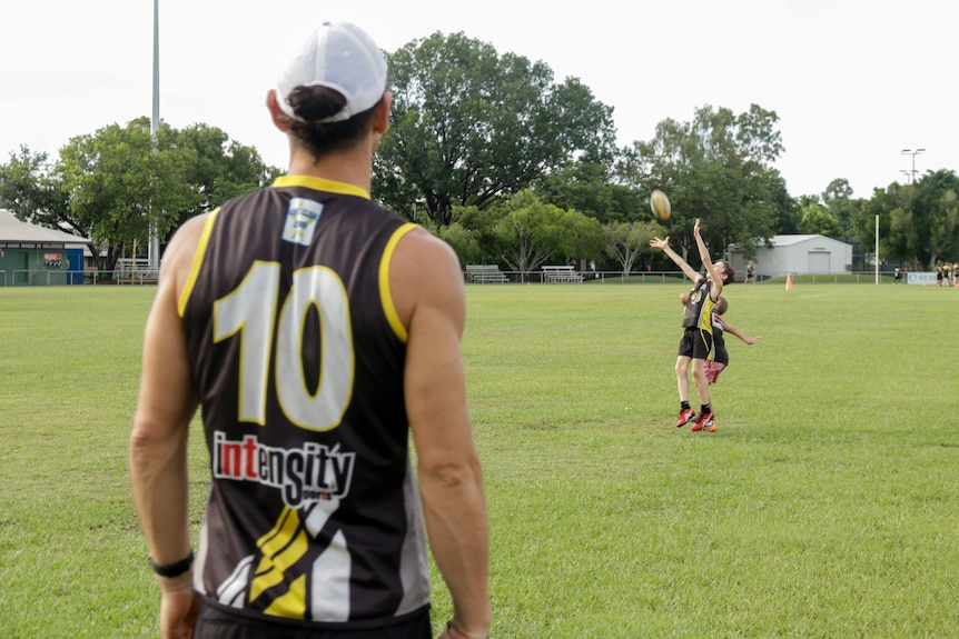 Cameron Ilett is seen in the foreground with his children trying to mark a football in the background.-