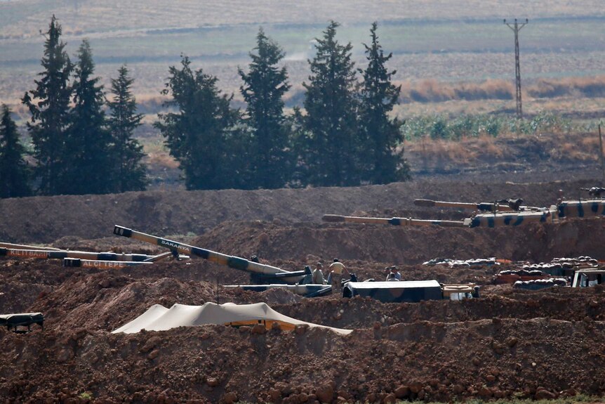 Turkish soldiers are seen on top pf tanks holding their positions near the border.