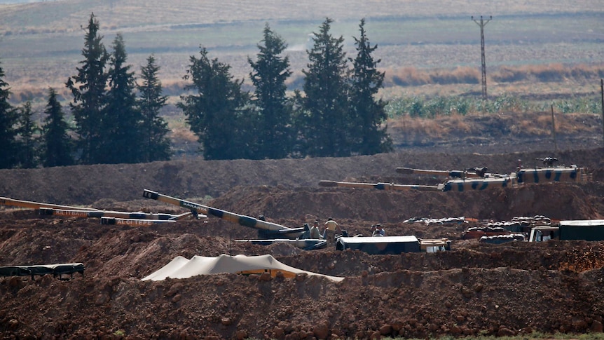 Turkish soldiers are seen on top pf tanks holding their positions near the border.