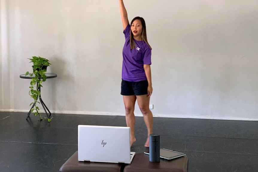 Ms Chan holds her arm above her head as she looks at her laptop.