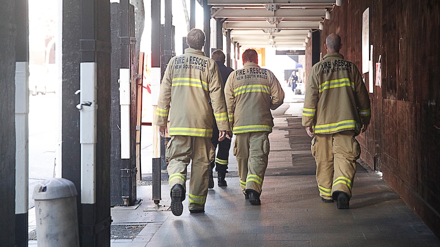 Emergency services crews walk under an awning at Martin Place, Sydney to attend to a gas leak