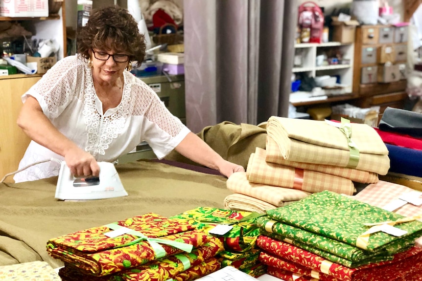 Woman irons material in haberdashery store.