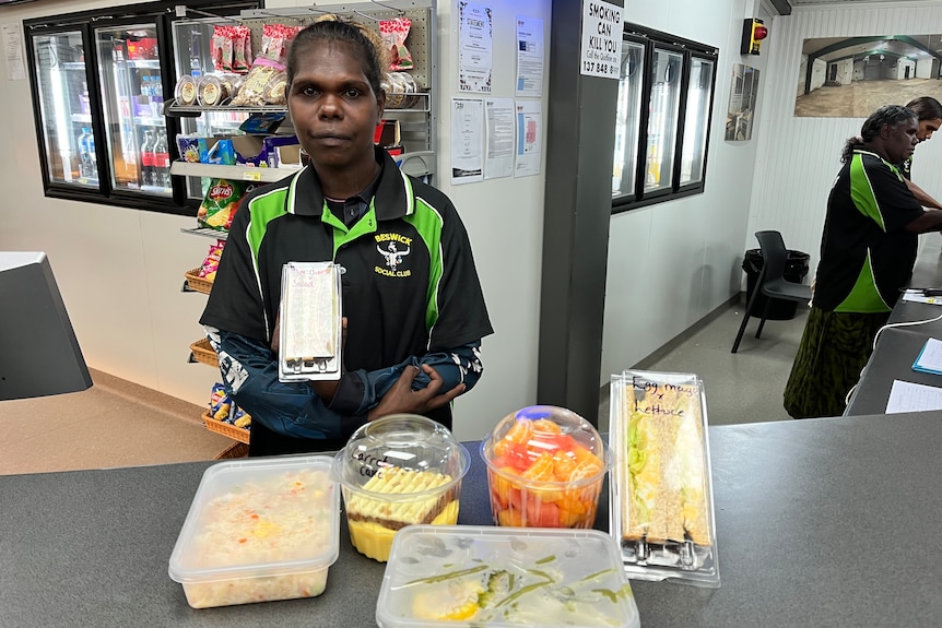 an aboriginal woman stands behind a counter with fresh food
