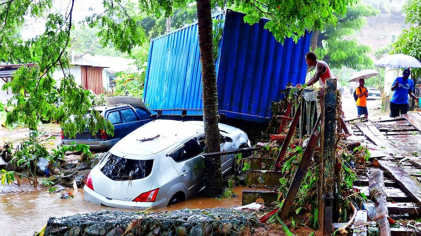 A man inspects cars that have been washed away by floodwaters.