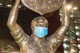 A statue of Wally Lewis in front of Suncorp Stadium (Lang Park) has a surgical face mask on it.