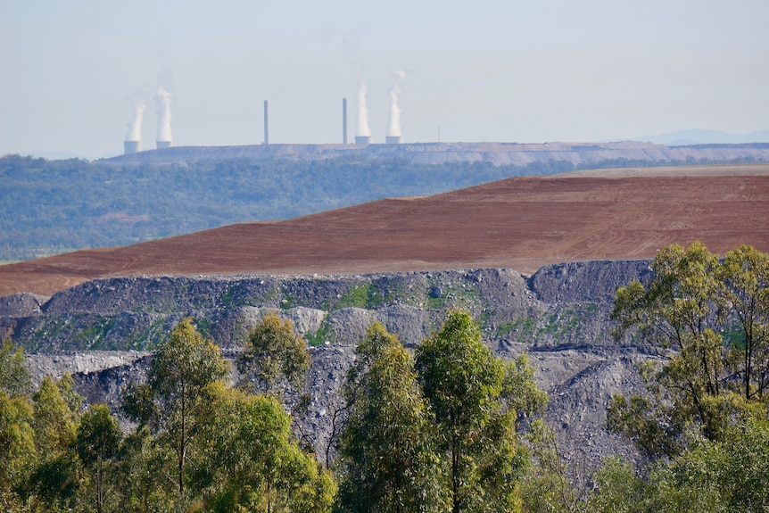 Distance shot of a coal mine with chimneys in the background.