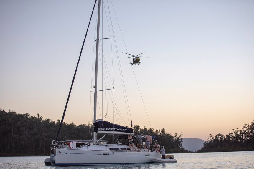 RACQ CQ Rescue helicopter hovering above the Queensland Yacht Charters boat, with people on board.