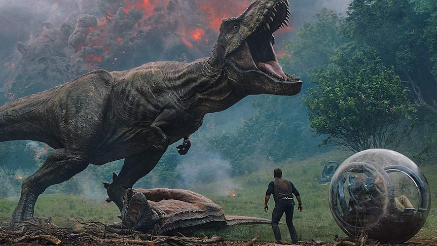 Chris Pratt's character is diminished by an enormous t-rex standing in front of an erupting volcano.