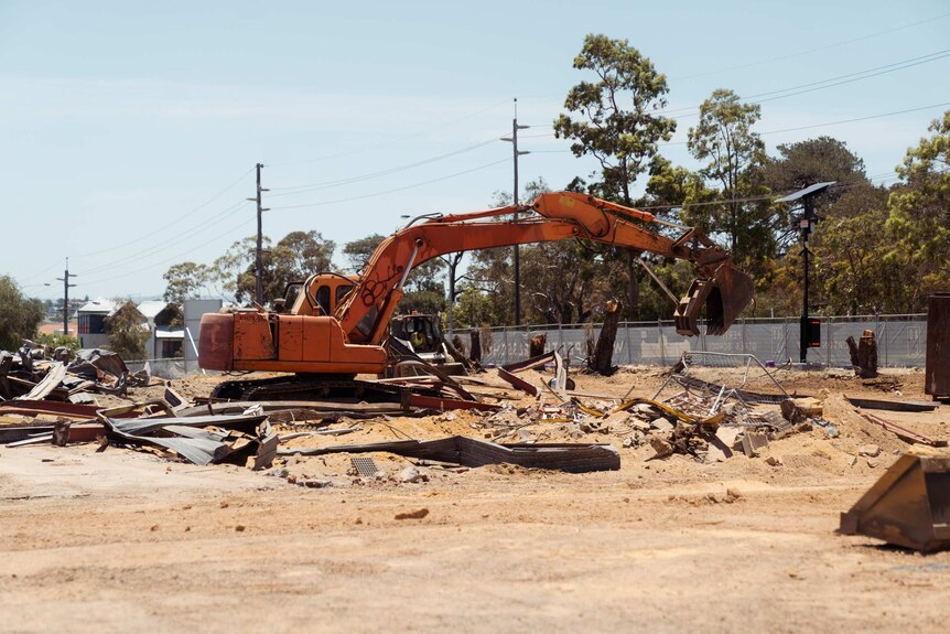 An excavator sits on the site, surrounded by bits of metal.