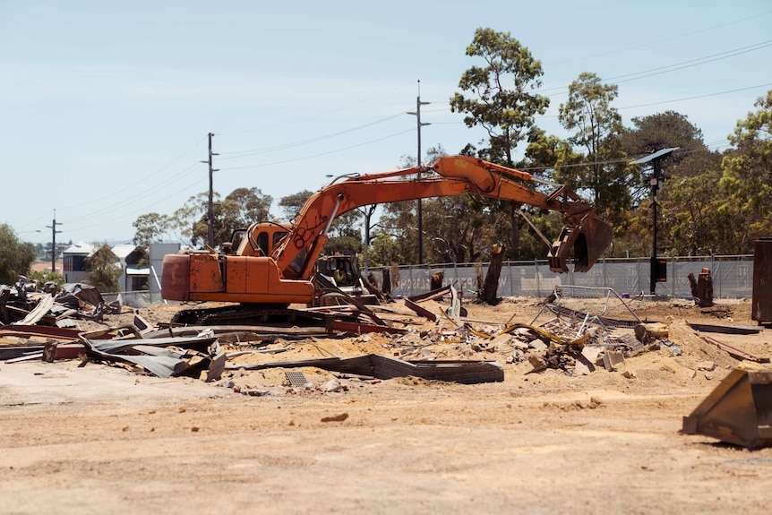 An excavator sits on the site, surrounded by bits of metal.