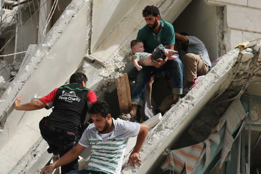 Syrian men remove a baby from rubble in Aleppo
