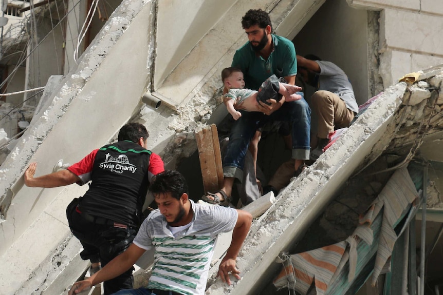 Syrian men remove a baby from rubble