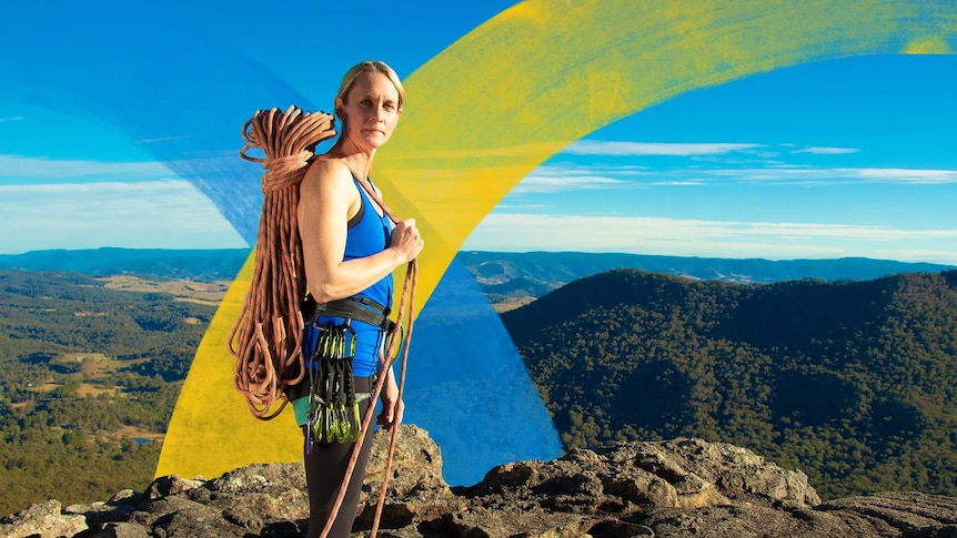 Woman in rock climbing gear holds a bunch of rope over her shoulder while standing at Sunset Rock Lookout.