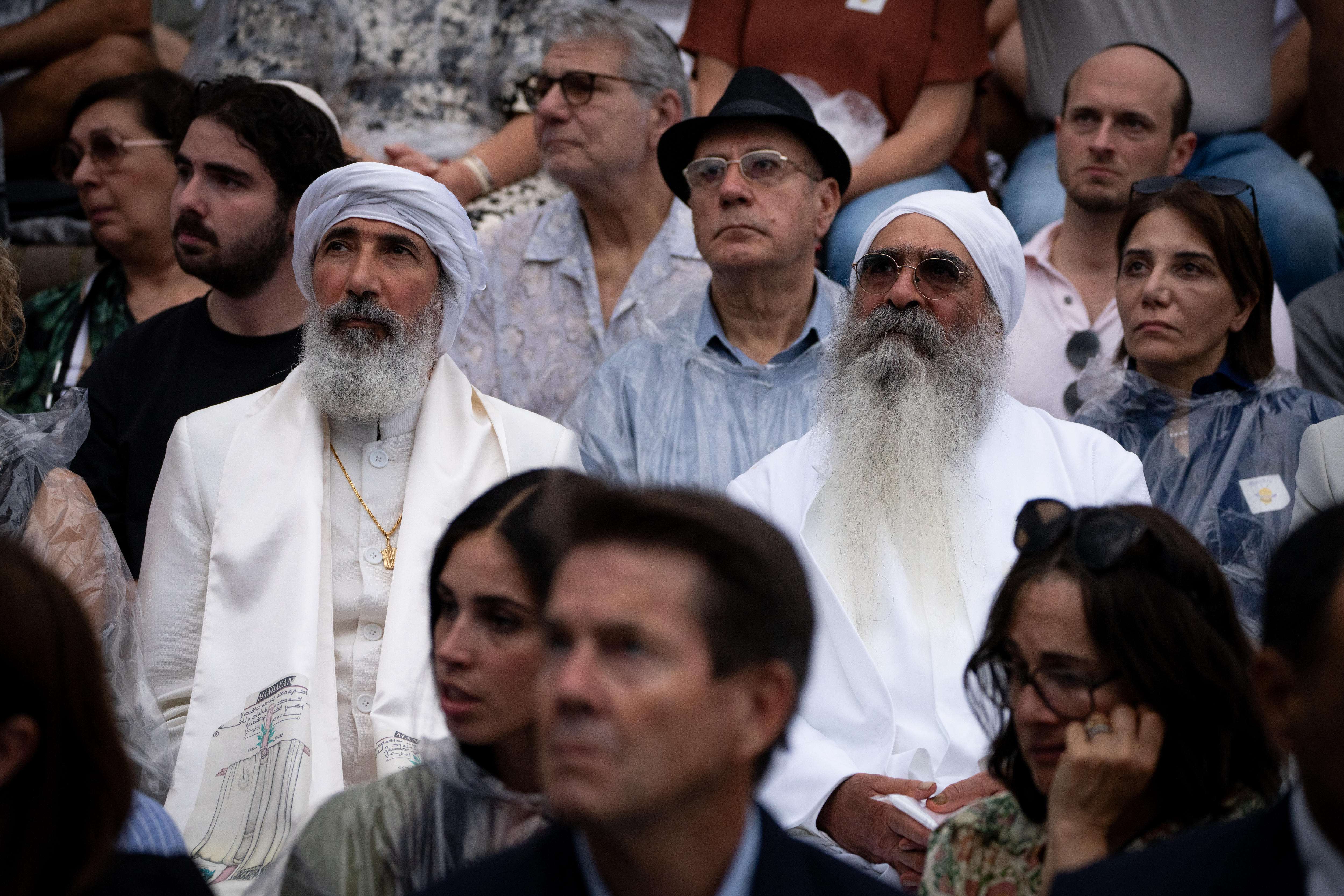 Dois homens parados no meio de uma multidão observando.