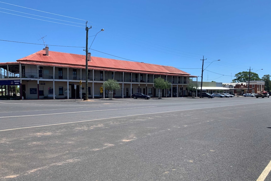 Large, double storey hotel in background, with wide bitumen street in foreground.
