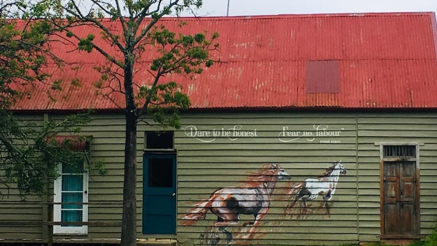 Rd roof, green boards and a mural of two horses galloping