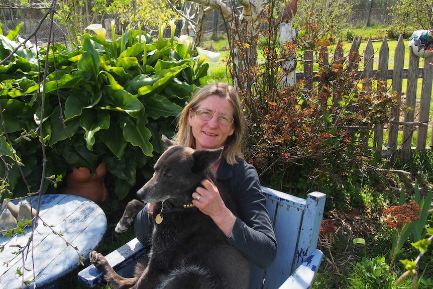 Woman sitting in a garden with a dog on her lap