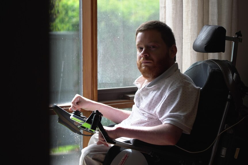 Man sitting in a wheelchair next to a window.