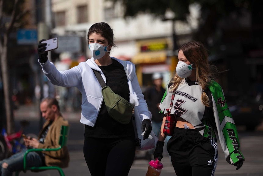 Two women take a selfie as they wear face masks in Tel Aviv, Israel.