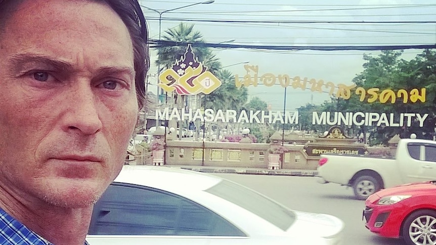 Brenton McArthur looks at the camera while standing in front of a sign in Indonesia.