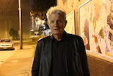 Reverend Bill Crews looks to the camera underneath a tunnel at nighttime.